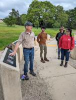 Adult man explains images on Eldridge Memorial column to three students
