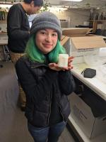 SSU Student displaying small white milk-glass jar of cosmetic cream for the camera.